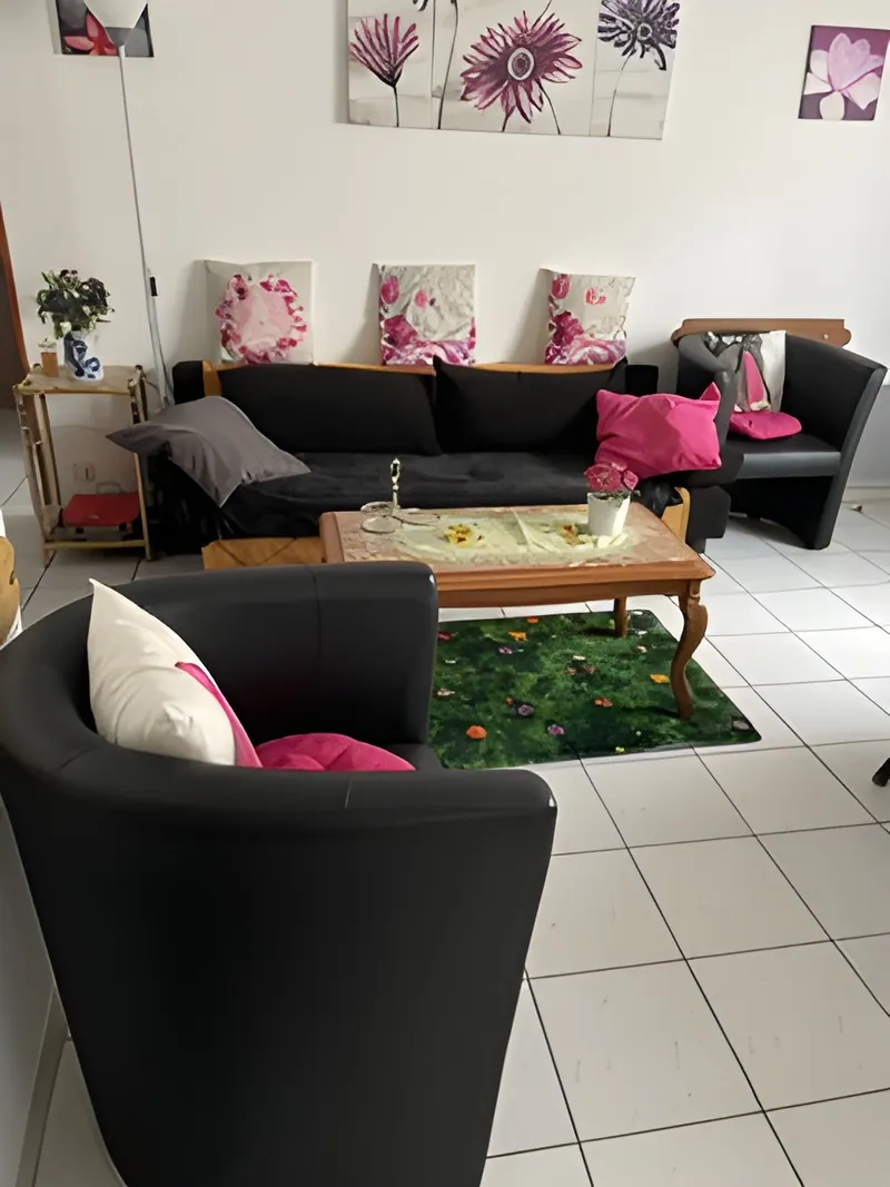 Séjour de l'appartement Isabelle : canapé, deux fauteuils et table basse sur carrelage clair